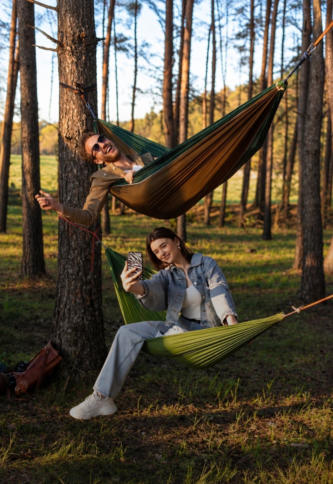 Couple relaxes in colorful hammocks while enjoying a sunny pine forest